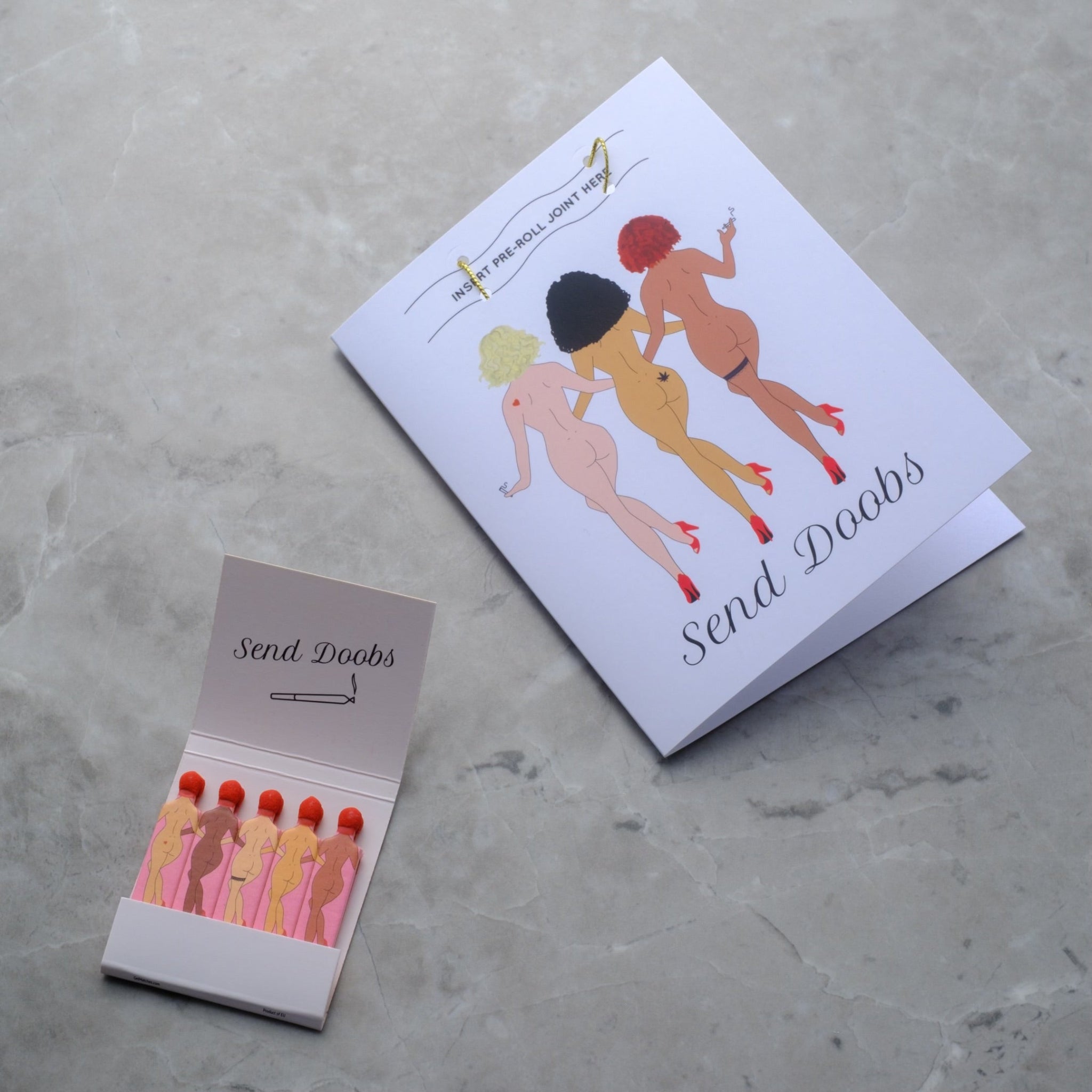 Rogue Paq x Kush Kards 'Send Doobs' greeting card featuring a built-in slot for holding a pre-rolled joint; styled with matching vintage-style SendNudes matches for a complete cannabis lover's gift set.