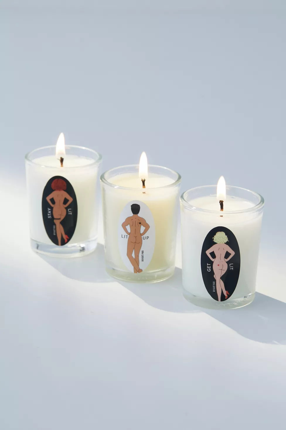 Rogue Paq SendNudes trio of massage candles on a white background with the hemp wicks lit.