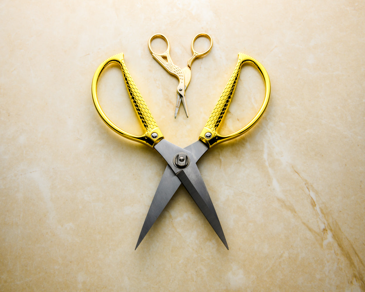 XL snake scale utilty scissors next to Rogue Paq small crane scissors to show scale of item. Both scissors are set on a neutral marble background.