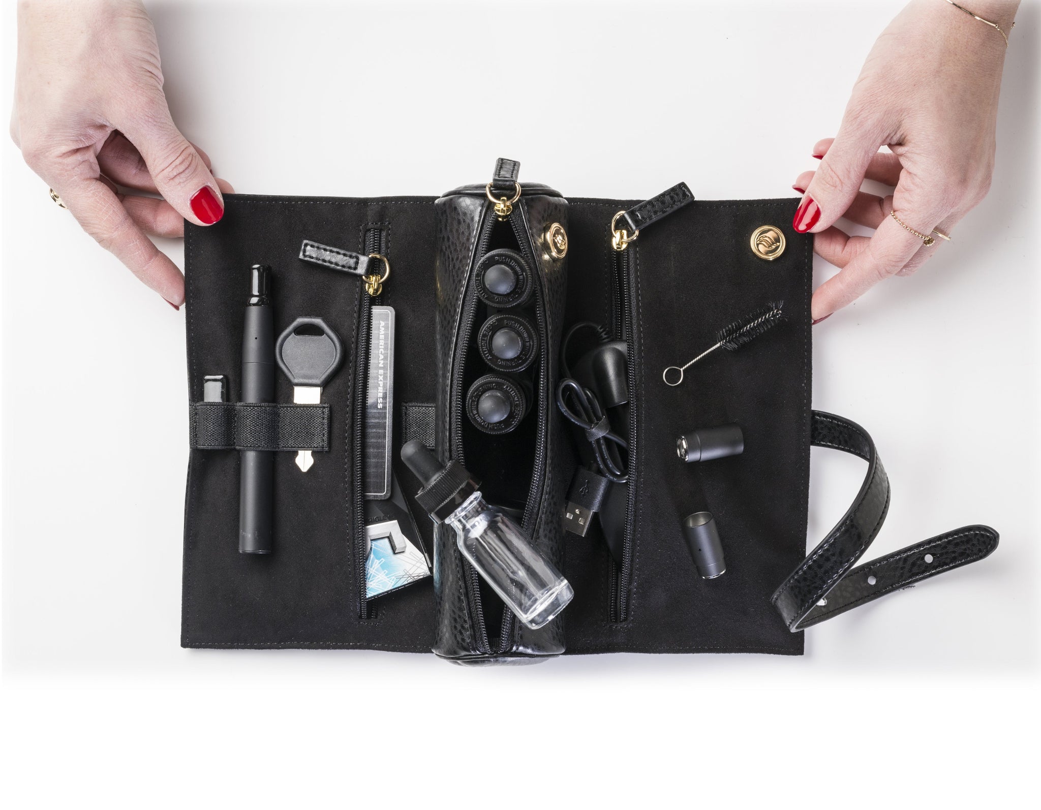 A close-up of a woman’s hands unfolding the black vegan leather cannabis carrier. The shot emphasizes the supple, high-quality texture of the sustainable materials and the premium feel of the hand-skived edges.