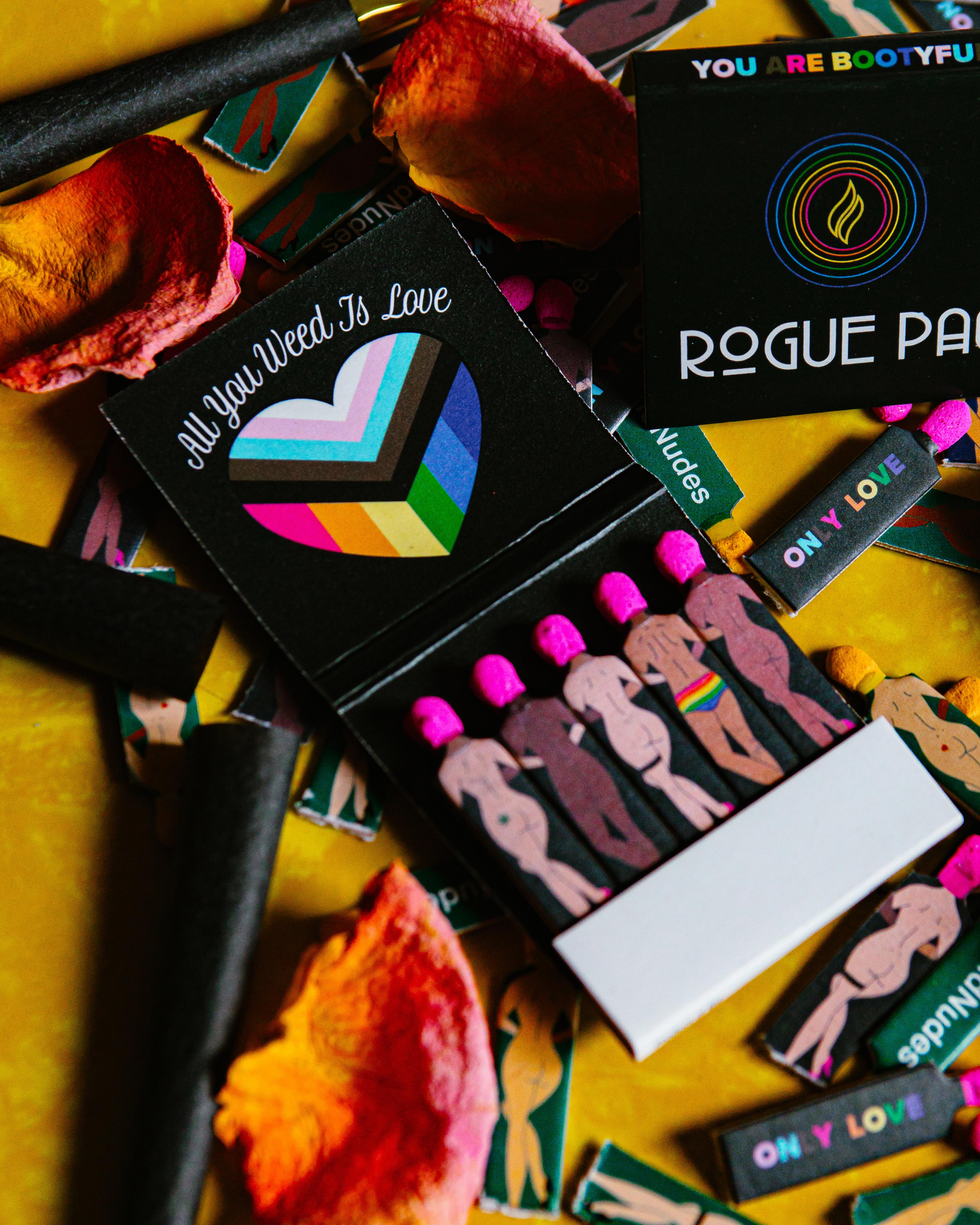 Single book of Rogue Paq SendNudes Matches highlighting the detailed 'All You Weed Is Love' illustration with vibrant colors and retro typography on high-quality stock