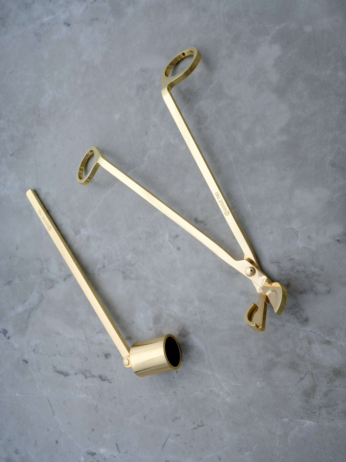 A luxury two-piece candle care set in a high-polish gold finish. The set includes a wick trimmer and a candle snuffer with a pivoting head, all featuring sleek, ergonomic handles and a minimalist, luxury aesthetic.