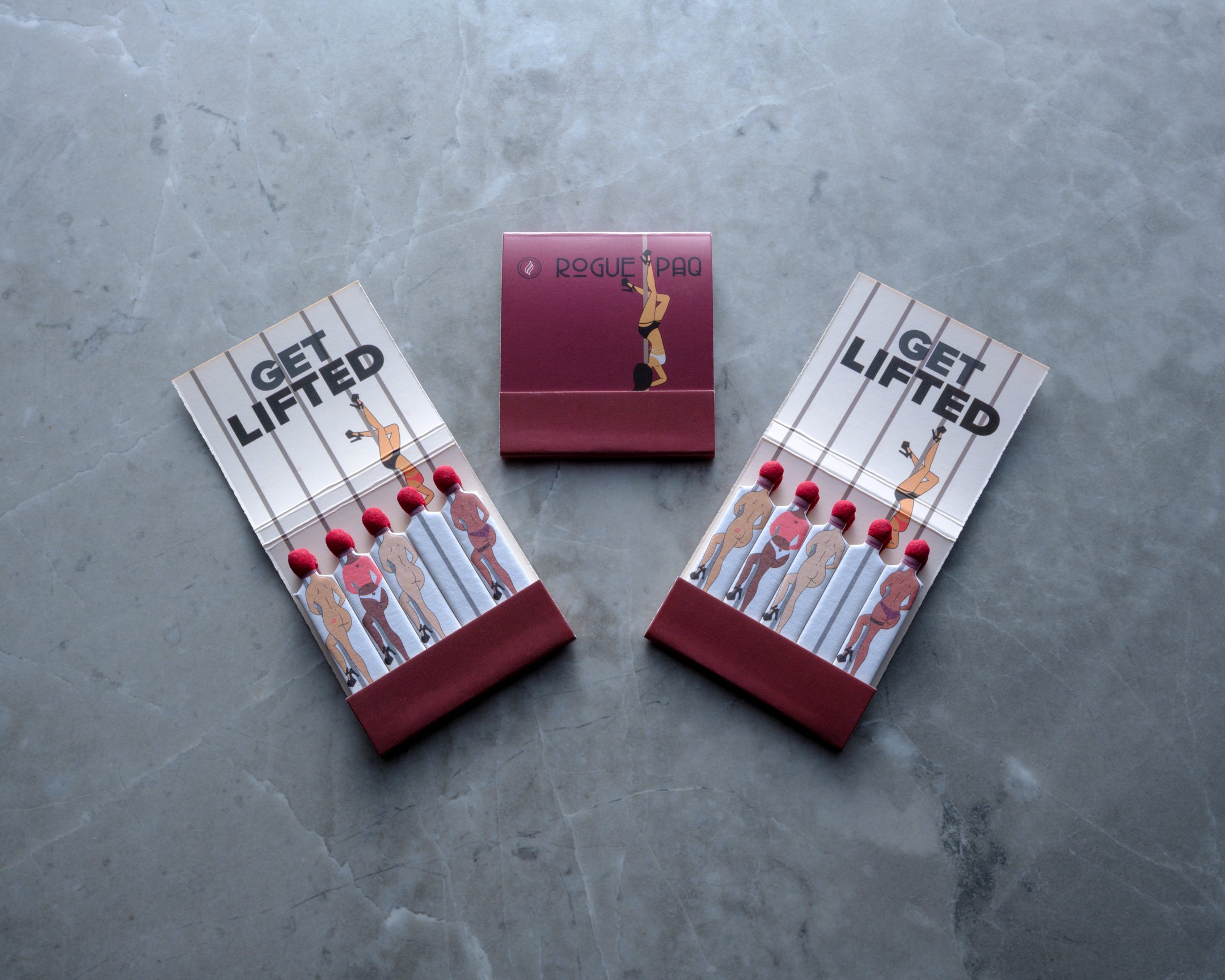 Set of three Rogue Paq matchbooks featuring the 'Get Lifted' pole dancer motif; printed on high-quality cardstock for a sophisticated yet whimsical gift.