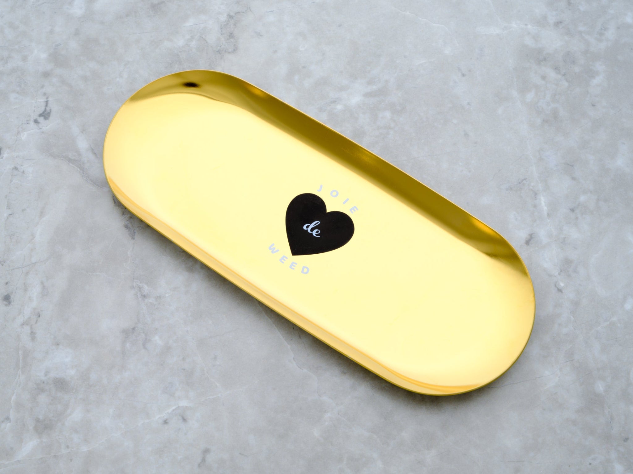 A luxury gold-toned travel rolling tray made from high-shine stainless steel. The tray features a minimalist, shallow-well design with the 'Joie de Weed' graphics in black and white.