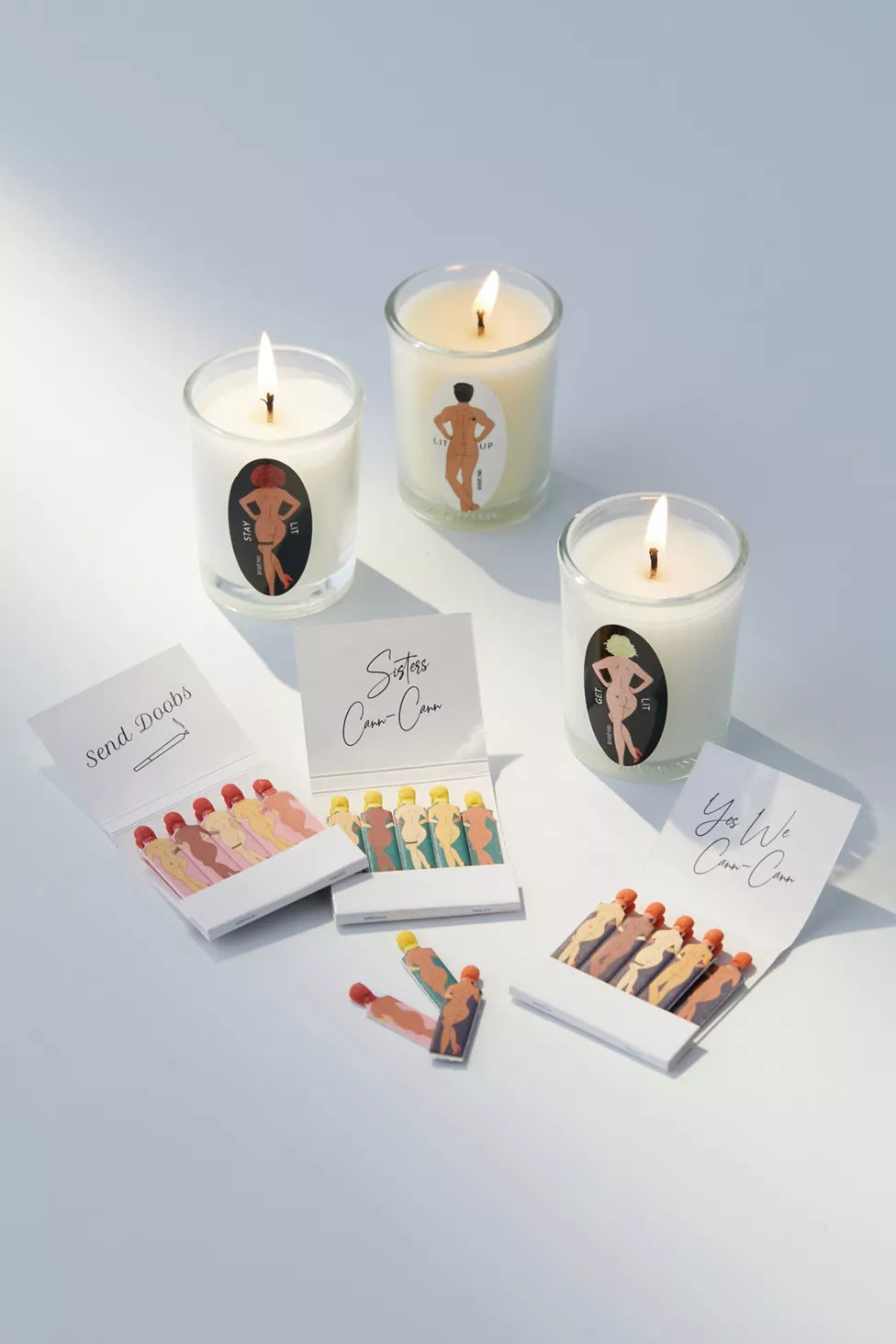 3 massage candles lit with 3 open matchbooks to represent the contents of the SendNudes candle gift set which is part of the Rogue Paq line up of cute smoking accessories.