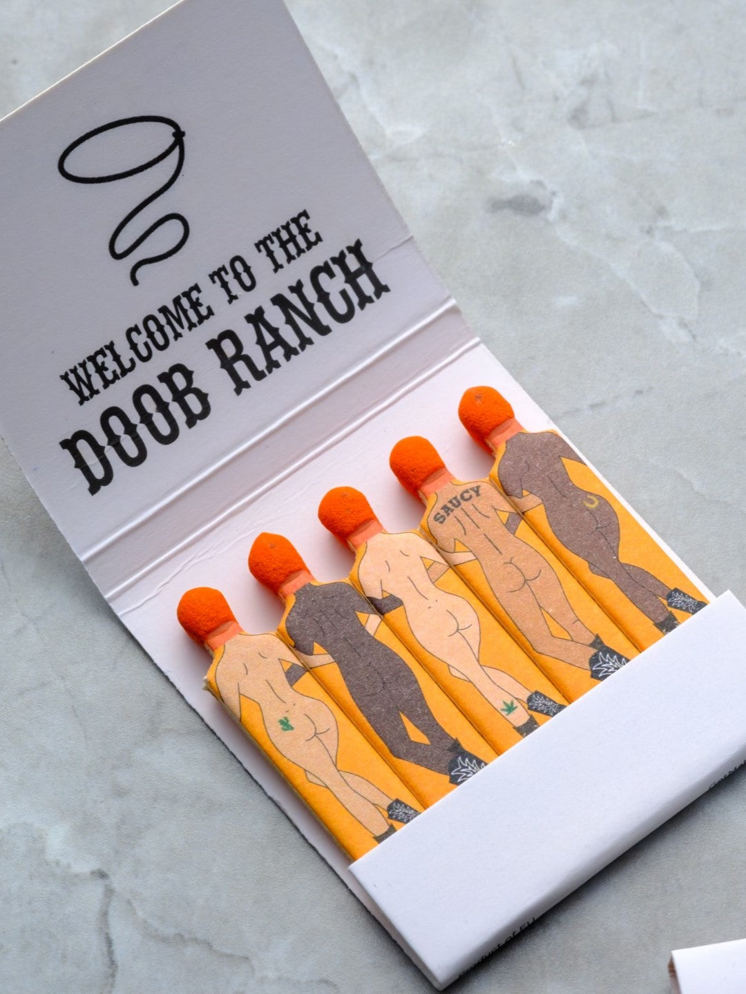 SendNudes Matchbooks: Welcome to the Doob Ranch featuring cowboys and cowgirls in a diverse range of skin tones to celebrate an elegant cannabis ritual.