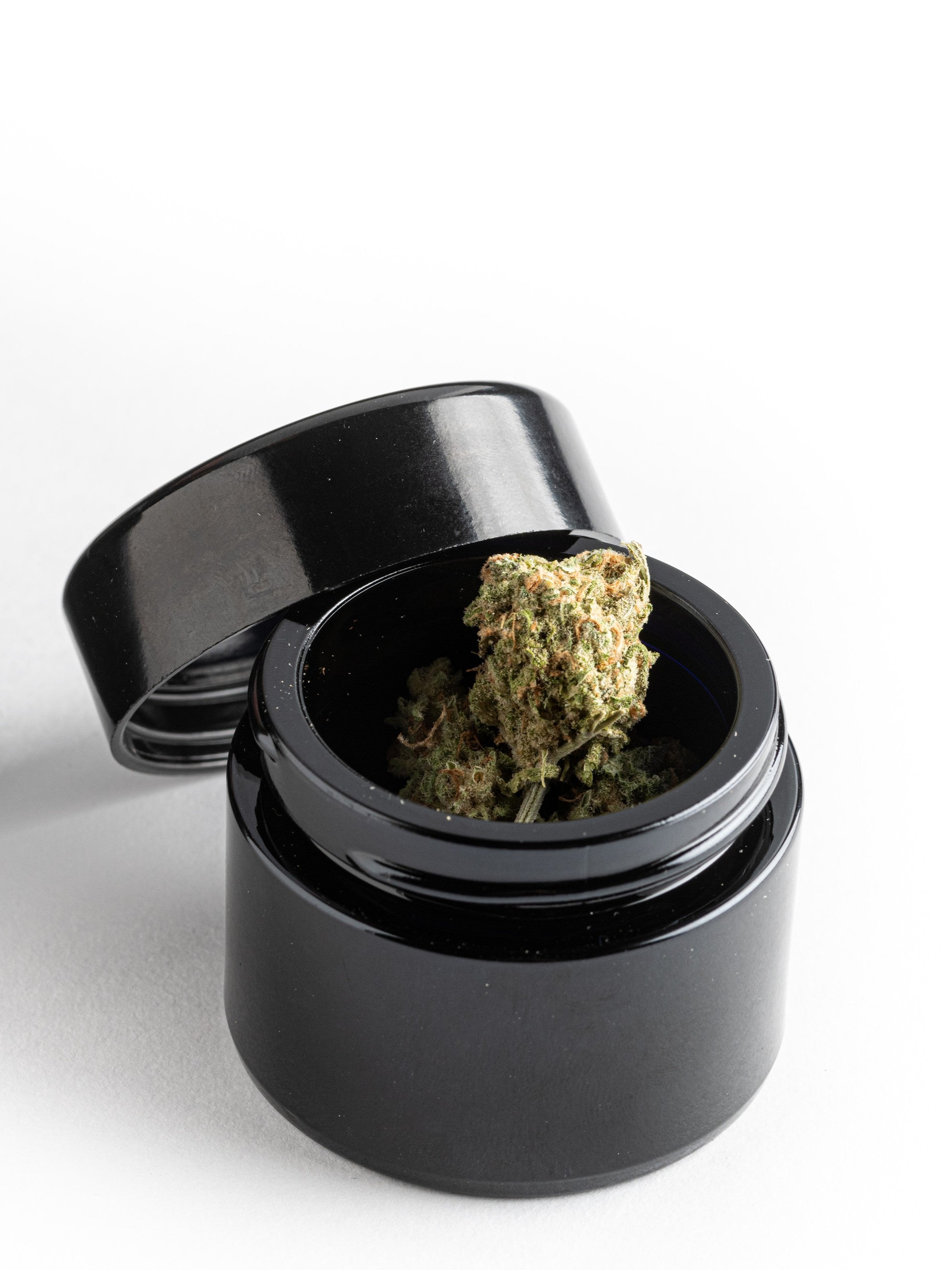 The 1oz glass jar head on to demonstrate its compact, travel-friendly scale. The sleek, monolithic design is discreet and fits perfectly into the side pockets of a Rogue Paq Ritual Case. When sealed with the lid, the jar is airtight.