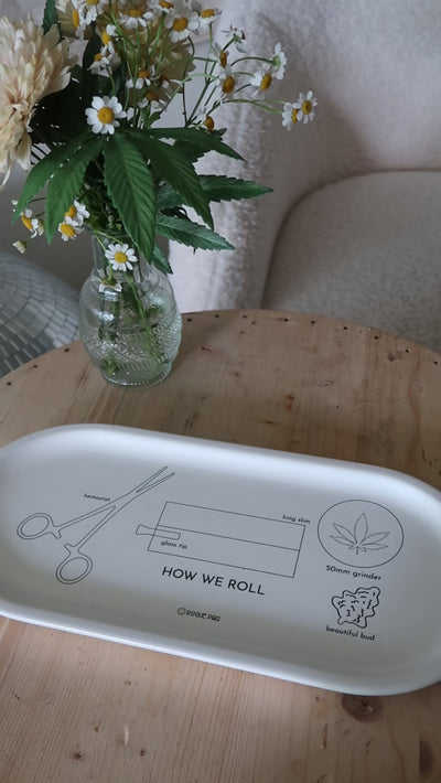 Close-up of the 'How We Roll' porcelain valet tray showing step-by-step black line illustrations of hands rolling a joint; a functional and artistic guide for the modern smoker.