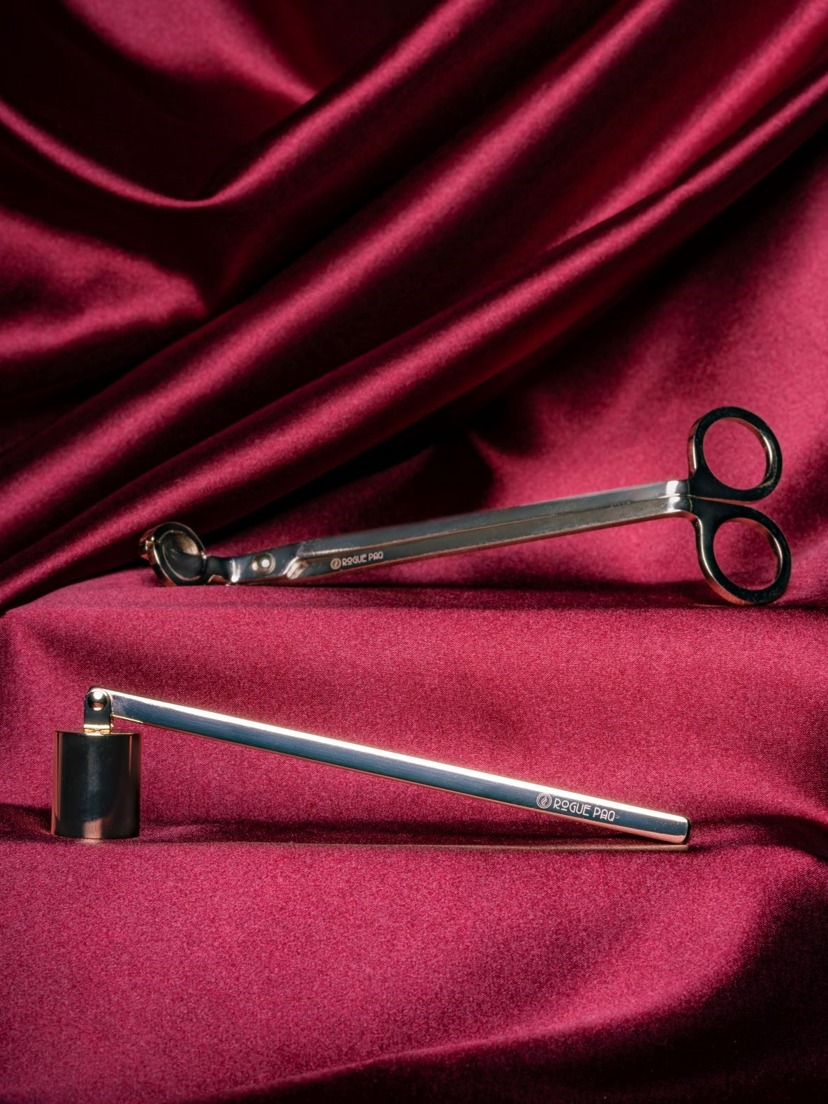 A luxury two-piece candle care set in a high-polish gold finish. The tools are elegantly arranged on red satin. The set includes a wick trimmer amd a candle snuffer with a pivoting head all featuring sleek, ergonomic handles and a minimalist, luxury aesthetic. Perfect as a hostess gift.
