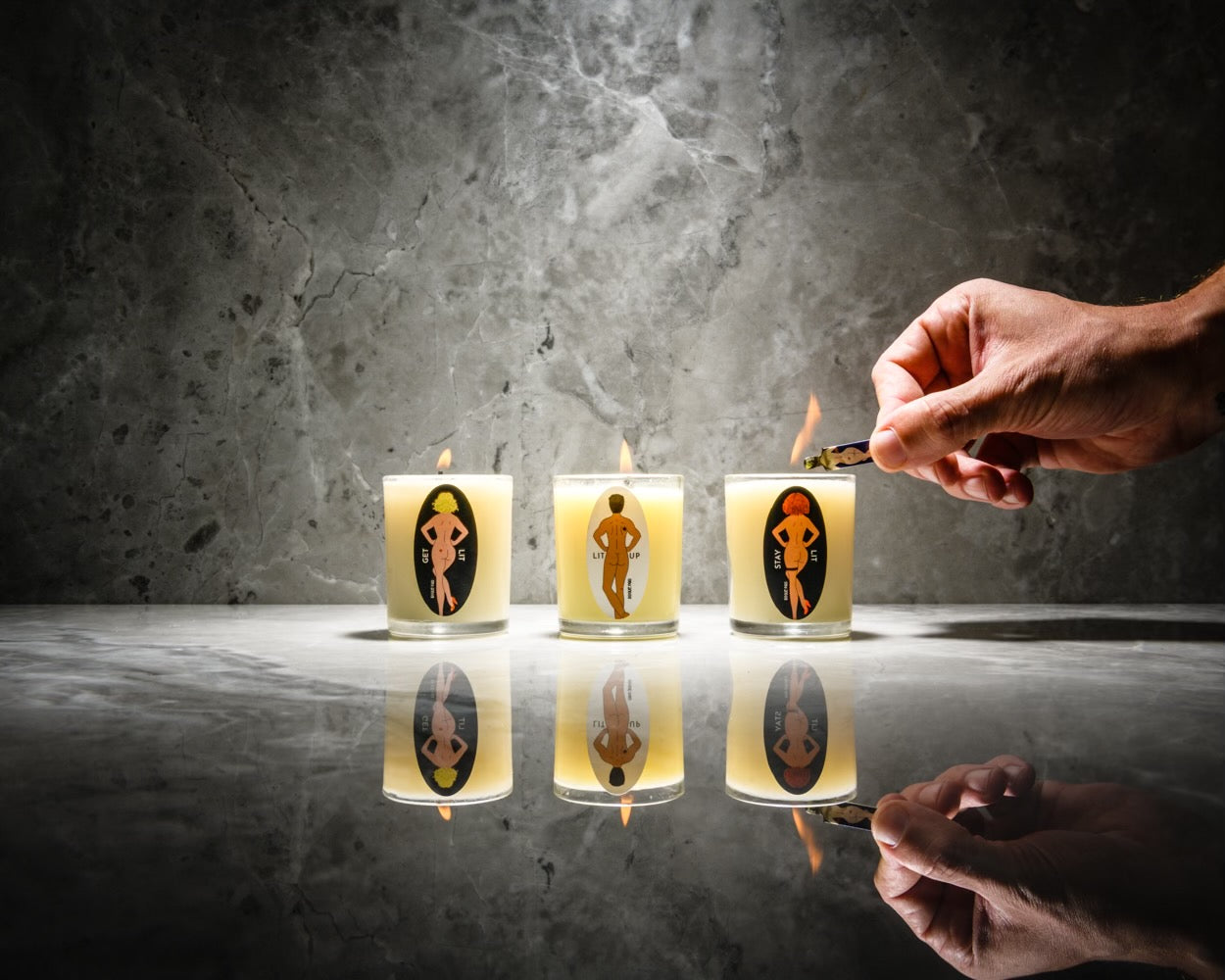 A detailed shot of three all natgural hand poured SendNudes candles  from the SendNudes collection. The  candle illustrations feature diverse, artistic nude figures with varying skin tones and hair colors in a high-kick dance pose, representing a celebration of body positivity and inclusivity.
