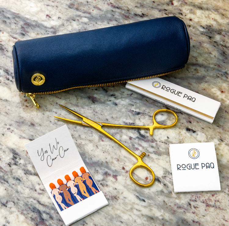Close up on the navy solo paq. Mini Ritual Gift Set laid out with closed navy Solo Paq cannabis case and gold hemostats and matches. Perfect kit for the refined cannabis enthusiast