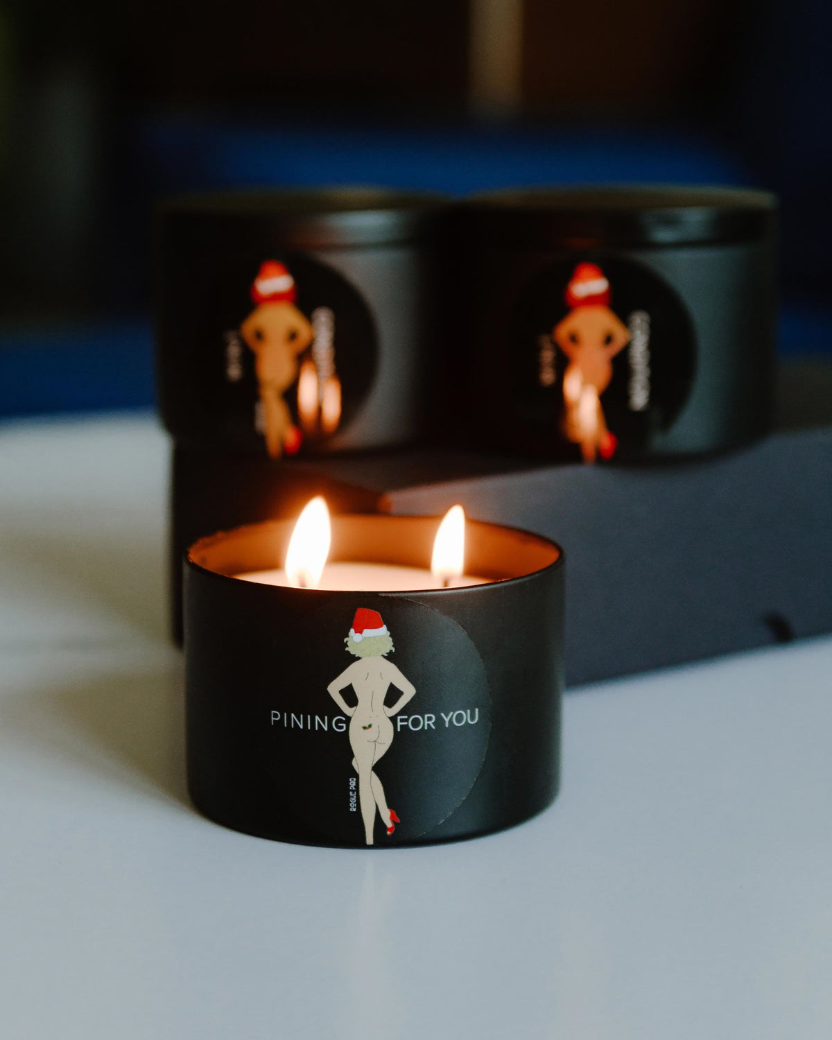 Lit Pining For You holiday candle styled in a cozy home setting; dual hemp wicks providing a warm glow and fresh winter forest scent