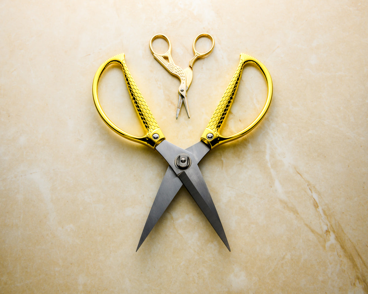 XL snake scale utilty scissors next to Rogue Paq small crane scissors to show scale of item. Both scissors are set on a neutral marble background.